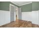 Green bedroom with hardwood floors, wainscoting, neutral paint, and two gray paneled doors at 7112 Camp Side Ct, Raleigh, NC 27613