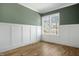 Well-lit bedroom with hardwood floors, wainscoting, neutral paint, and double windows at 7112 Camp Side Ct, Raleigh, NC 27613
