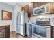 Efficient kitchen with stainless appliances, including a refrigerator, microwave, and stove with dark wooden cabinets at 714 Cupola Dr, Raleigh, NC 27603