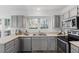 Charming kitchen with gray cabinets, stainless appliances and a double sink under a garden window at 105 Solstice Cir, Cary, NC 27513