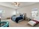 Spacious bedroom with a ceiling fan, carpet flooring, a grey bed with blue bedding, and multiple windows at 1610 Stone Rd, Durham, NC 27703