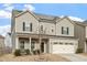 Inviting two-story home featuring solar panels, a two-car garage, and a covered front porch at 1610 Stone Rd, Durham, NC 27703