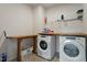 Well-lit laundry room with a front-load washer and dryer set, complemented by a folding table and overhead shelving at 1610 Stone Rd, Durham, NC 27703