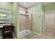 Bright main bathroom with a large mirror, walk-in shower, and a vanity area, tiled in neutral shades at 1610 Stone Rd, Durham, NC 27703