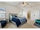Bright main bedroom with a bed featuring blue patterned bedding, a ceiling fan, and carpet flooring at 1610 Stone Rd, Durham, NC 27703