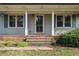 Inviting front porch featuring a classic wood door, brick steps, and views of the surrounding landscaping at 245 Cedar Crk Rd, Franklinton, NC 27525