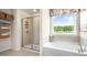 Bright bathroom featuring a soaking tub, stand up shower with neutral tile, and open shelving at 302 Umstead St, Sanford, NC 27330