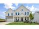 Inviting two-story home featuring a covered front porch, classic white siding, and a stone-accented garage at 314 Umstead St, Sanford, NC 27330