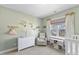 Cozy Bedroom featuring a crib, glider, and dresser with decorative shelving at 415 Mariah Towns Way, Garner, NC 27529