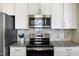 Modern kitchen featuring stainless steel microwave, oven, granite counters and tile backsplash at 415 Mariah Towns Way, Garner, NC 27529