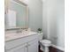 Powder room featuring white vanity, mirror, modern fixtures and hardwood floors at 415 Mariah Towns Way, Garner, NC 27529
