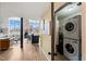 Open living space featuring a modern kitchen with breakfast bar, exposed brick, and in-unit laundry closet at 614 Capital Blvd # 229, Raleigh, NC 27603