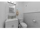 Simple powder room featuring a gray tiled wall, modern vanity, and a standard toilet at 101 Mantle Dr, Clayton, NC 27527