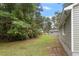 View of the side and backyard, featuring green siding and a tree-lined property at 1213 Freeman Dr, Sanford, NC 27330