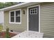 Close-up of the home's entrance, showcasing the gray door, green siding, and white trim at 1213 Freeman Dr, Sanford, NC 27330