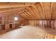 Unfinished attic space with exposed beams, plywood floor, and insulation on the walls at 12507 N Roxboro St, Rougemont, NC 27572