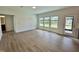 Bright, open living room with wood floors, three windows, and a door to the outside at 167 S Harvest Ridge Way # Homesite 223, Wilson's Mills, NC 27520