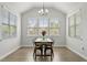 Well-lit dining room with vaulted ceiling, a rustic dining table, and a view of the outdoors through three large windows at 1872 Stagecoach Trl, Wendell, NC 27591