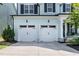 Two-car garage with matching doors, black fixtures, and stone trim for added curb appeal at 1872 Stagecoach Trl, Wendell, NC 27591