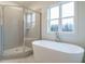Modern bathroom showcasing a freestanding tub, glass shower, and a serene window view at 213 Big Bradley Dr, Wendell, NC 27591
