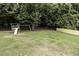 Landscaped backyard with a playset and a surrounding fence in a partially wooded area at 2570 Sweet Bay Rd, Rocky Mount, NC 27804
