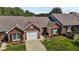 Aerial view showcasing a brick home, attached garage, landscaped yard, and driveway at 3027 Maple Ave # D2, Burlington, NC 27215