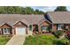 Brick home featuring an attached garage, green door, and mature landscaping at 3027 Maple Ave # D2, Burlington, NC 27215