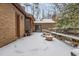 Brick home's backyard featuring a snow-covered patio area with wooden railing and chimney at 3412 Hackney Ct, Raleigh, NC 27613