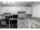 Functional kitchen with white cabinets, black appliances, and stone-look countertops at 401 Oak Hollow Ct, Raleigh, NC 27613