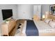 This staged bedroom features light wood floors, a blue throw blanket, and an adjacent closet at 475 Bramble Ln, Clayton, NC 27527