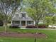 Charming home with lush green lawn and mature landscaping, featuring a cozy covered porch and a mix of stone and siding at 1005 Keith Rd, Wake Forest, NC 27587