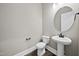 Stylish half bathroom with pedestal sink, round mirror, and modern fixtures at 1005 Keith Rd, Wake Forest, NC 27587