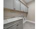 Bright laundry room with gray cabinets, white sink, and tile floors at 1005 Keith Rd, Wake Forest, NC 27587