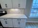 Kitchen counter featuring white cabinets with black handles, tile backsplash, and quartz countertops at 1063 Fairhaven Dr # 54, Mebane, NC 27302