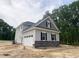 Side view of gray house features a white garage door, stone accents, and lush green trees at 1663 Keith Hills Rd, Lillington, NC 27546