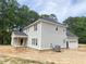 Angle view of a gray home featuring a side entry garage, and covered porch nestled among green trees at 1663 Keith Hills Rd, Lillington, NC 27546