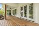 Covered back porch featuring wood flooring and white trim with views of the lush backyard at 212 Lynch Ave, Lillington, NC 27546
