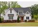Charming two-story home featuring white siding, a dark roof, an orange front door, and a well-manicured front yard at 212 Lynch Ave, Lillington, NC 27546