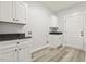 Functional laundry room with white cabinets, black countertops, a sink, and a convenient side door at 212 Lynch Ave, Lillington, NC 27546