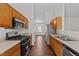 Modern kitchen featuring stainless steel appliances, wood cabinets, and dark laminate flooring at 224 Hartshorn Ct, Holly Springs, NC 27540