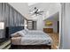 Bedroom with a striped duvet cover, hardwood floors, a ceiling fan, and stylish wood-paneled accent wall at 3506 Bellevue Rd, Raleigh, NC 27609