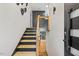 Home entryway with a wooden staircase, gray accent wall, and a modern black front door at 3506 Bellevue Rd, Raleigh, NC 27609
