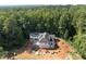 New construction aerial view of a home surrounded by mature trees and a cityscape in the distance at 3601 Alamance Dr, Raleigh, NC 27609