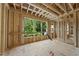 The wood framing is nearly complete, awaiting walls, and the large picture window frames the green trees outside at 3601 Alamance Dr, Raleigh, NC 27609