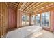 Unfinished living room showcasing pink insulation, wood framing, and large windows at 3601 Alamance Dr, Raleigh, NC 27609