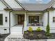 Inviting covered front porch with cozy seating, beautiful flowerbeds, and a white brick foundation at 4622 Durham Rd, Wake Forest, NC 27587