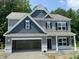 New two-story home with attached garage, blue shutters, and gray siding on a sunny day at 507 Olivia Crossing Ct # 20, Four Oaks, NC 27524