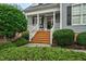 Inviting front porch with brick steps, white railings, and manicured greenery at 6489 Waters Edge Dr, Rocky Mount, NC 27803