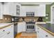 Kitchen features stainless steel oven, microwave and tile backsplash with white cabinets at 6489 Waters Edge Dr, Rocky Mount, NC 27803