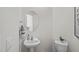 Bright half bathroom featuring a pedestal sink, round mirror, and neutral paint at 1914 Frost Dr, Haw River, NC 27258